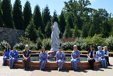 SSM Health St. Mary's Hospital nurses sitting in front of fountain with statue