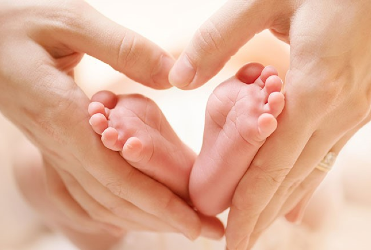 hands holding baby's feet in shape of a heart