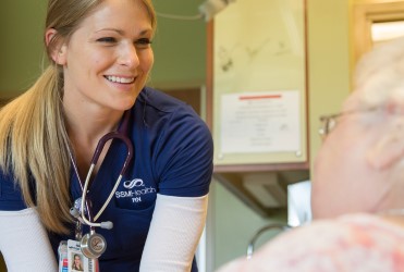 nurse smiling at a patient in bed