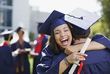 college student at graduation hugging another student